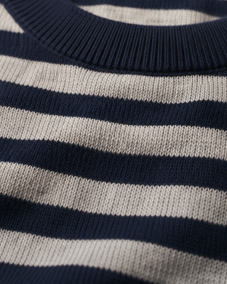 Close-up of a knit crewneck sweater with horizontal navy blue and off-white stripes, showing the ribbed collar and knit texture.